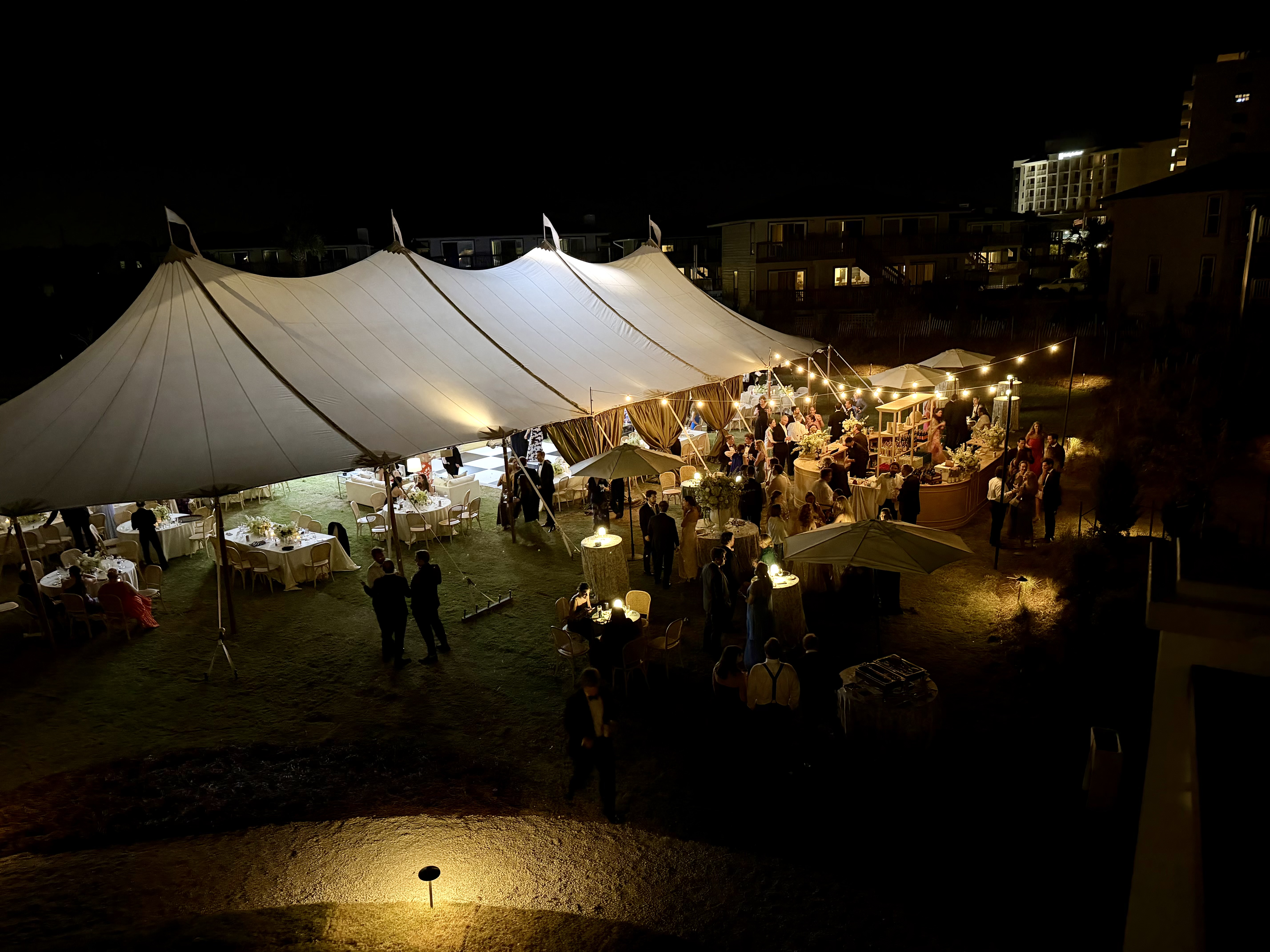 A sailcloth-tent reception glowing under string lights at The Surf Club