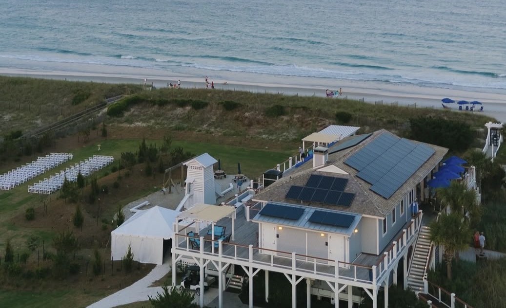 Aerial view of The Surf Club clubhouse, ceremony lawn, dunes and ocean at dusk
